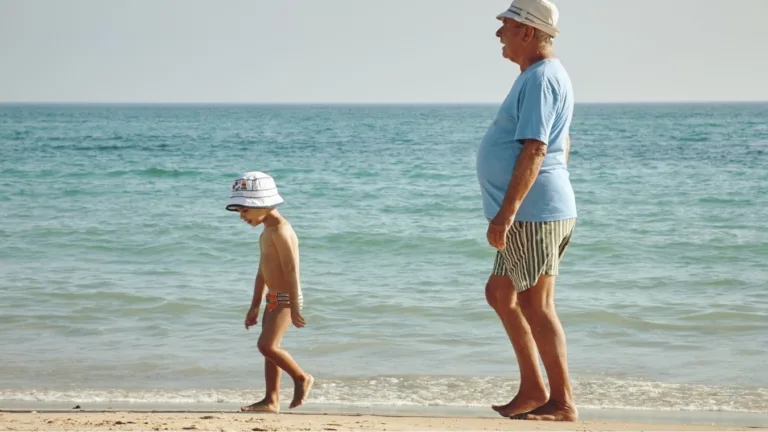 An adult and child walk on the beach; an ad for VIRTUOSO philanthropy.