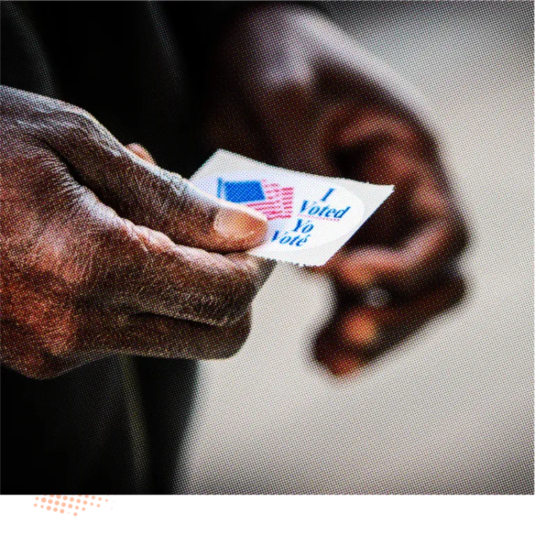 A close-up photo of a person's hands holding an "I Voted" sticker