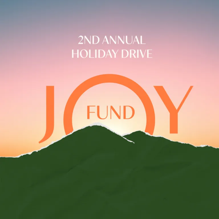 A sunrise rises above two green mountain peaks, frame in orange letters that read "2nd Annual Holiday Drive JOY FUND" with the fund within the center of the O.