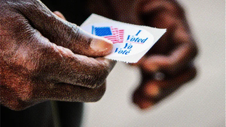 A close-up photo of a person's hands holding an "I Voted" sticker