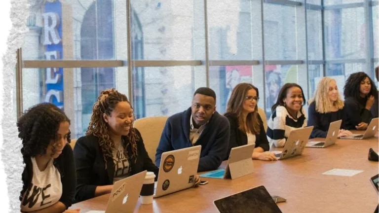Torn paper image of workers at a conference table with laptops engaging in a meeting