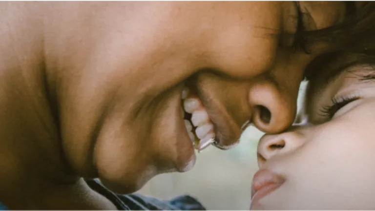 A close-up photo depicts the profile of a smiling mother, pressing the nose of her baby against her face