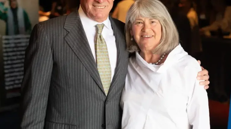 Two people embracing, one in a gray pinstripe suit and the other in a white blouse.