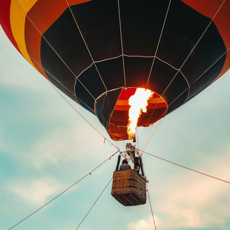 Hot air balloon with flame heating air against a blue sky.