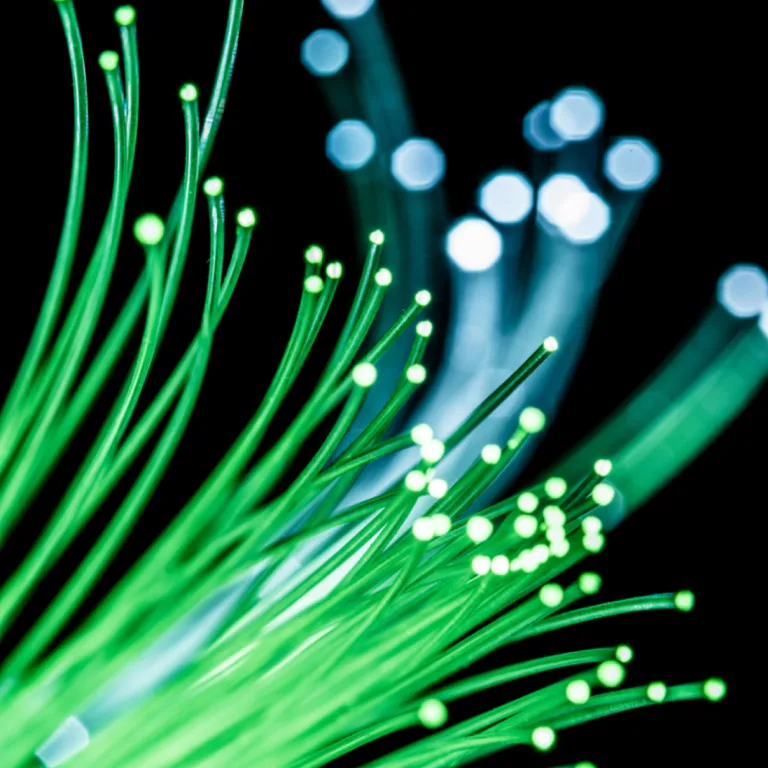 Glowing green fiber optic cables with blurred lights against a dark background.