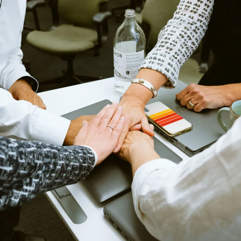 A group of people stacking hands in a gesture of teamwork and unity.