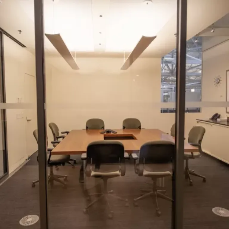 View through glass doors of an empty modern conference room with a table and chairs.