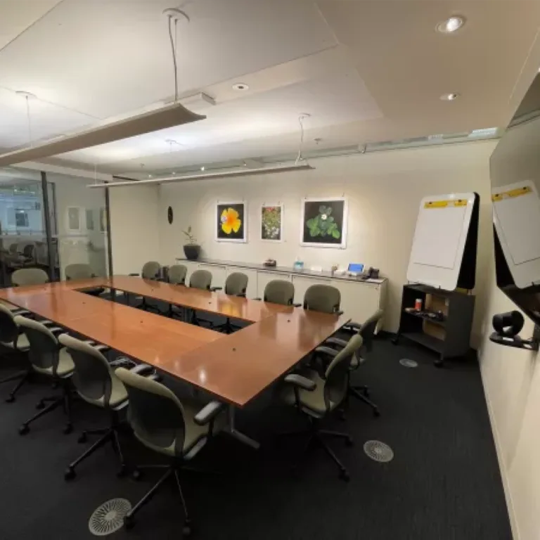 A modern conference room with a large table, chairs, and artwork on the wall.