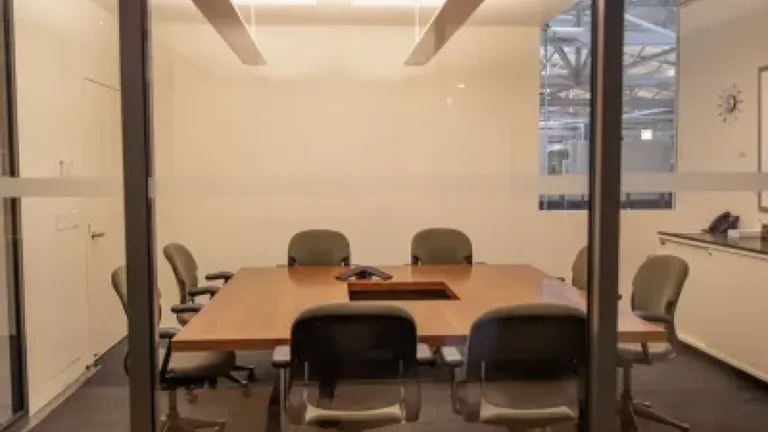 View through glass doors of an empty modern conference room with a table and chairs.