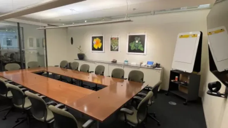 A modern conference room with a large table, chairs, and artwork on the wall.