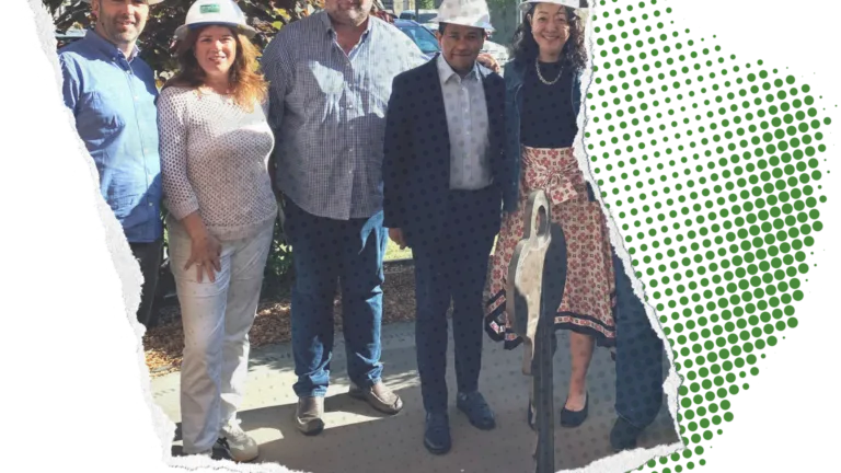 5 people in white hard hats, a mix of women and men, stand smiling and posed for the camera