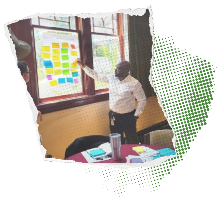 Person pointing at a board with colorful sticky notes in a meeting room.