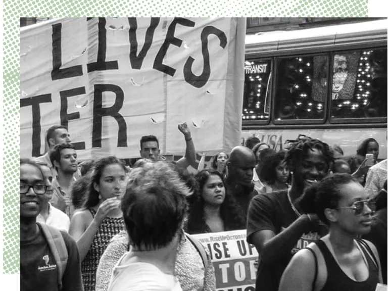 People at a demonstration holding a "Black Lives Matter" banner in a city street.