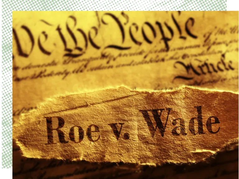 Close-up of "Roe v. Wade" text on torn paper over the US Constitution starting with "We the People".