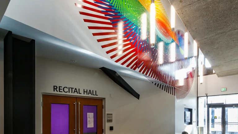Entrance to a recital hall with white neon lights against brightly colored designs above the doors