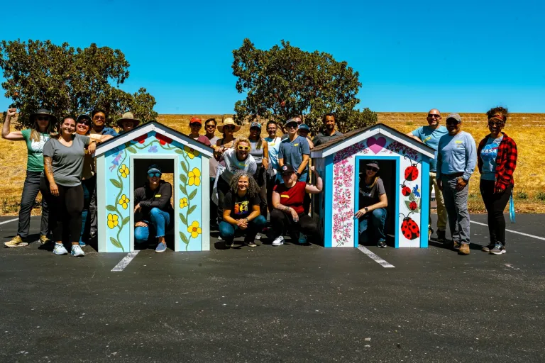 Staff members from MCF gathered around two playhouses they built for Habitat for Humanity
