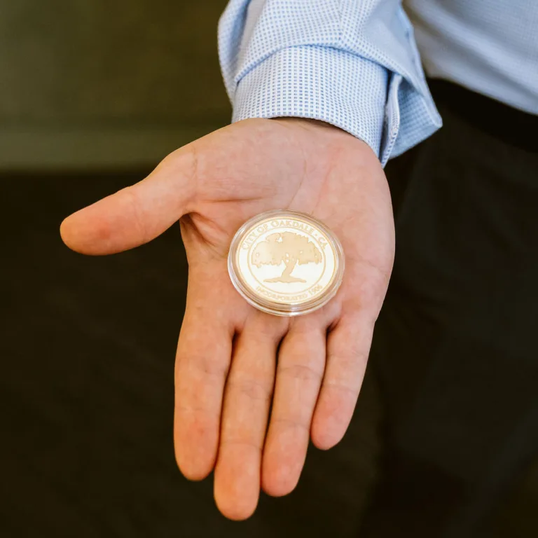 Person holding a large commemorative coin with the text "City of Oakdale" on it.