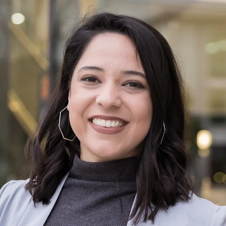 Headshot of Stephanie Martinez wearing a dark grey mock turtleneck and light grey sweater