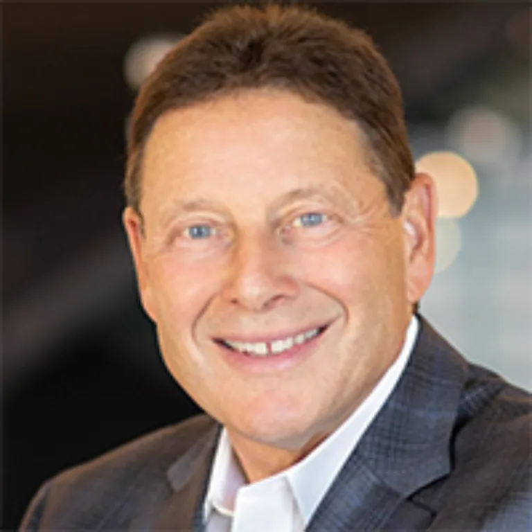 Headshot of Philip Feldman wearing a white dress shirt and brown jacket