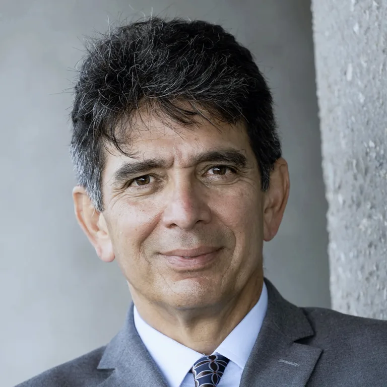 Headshot of Ralph Gonzalez wearing a white dress shirt and grey tie and jacket