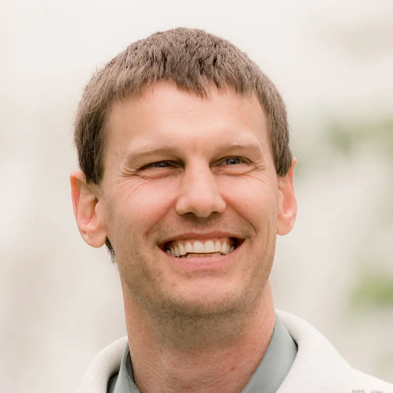 Headshot of Emory Horvath in a pale green dress shirt and beige jacket