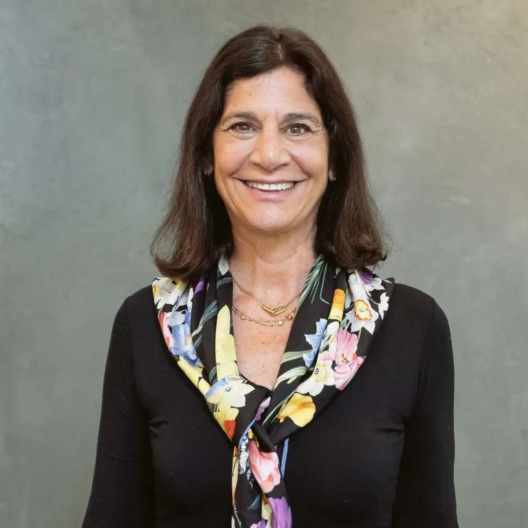 Headshot of Jennifer Urdan wearing a black shirt and floral scarf