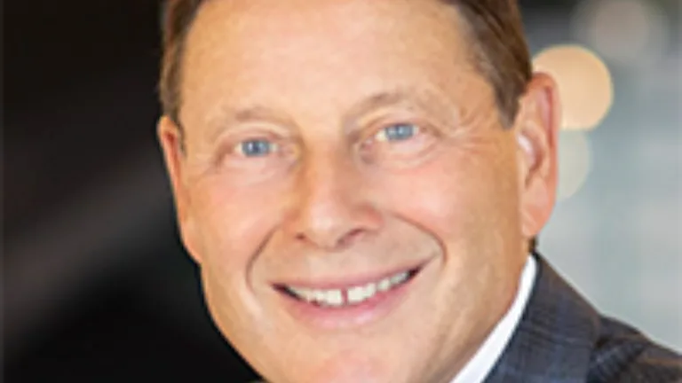 Headshot of Philip Feldman wearing a white dress shirt and brown jacket
