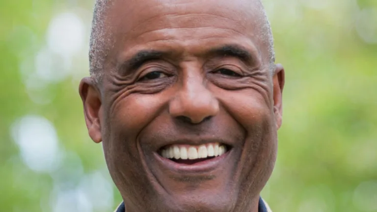 Headshot of Noah Griffin wearing a dark grey dress shirt and tan jacket