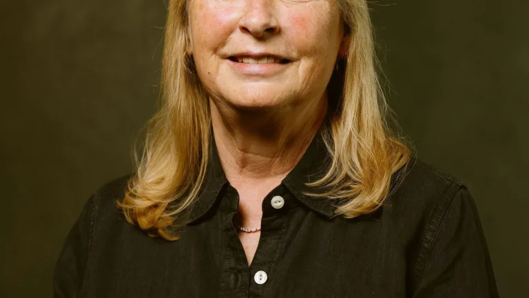 Image of Mary DiCarlo, smiling at camera, wearing a black shirt with white buttons